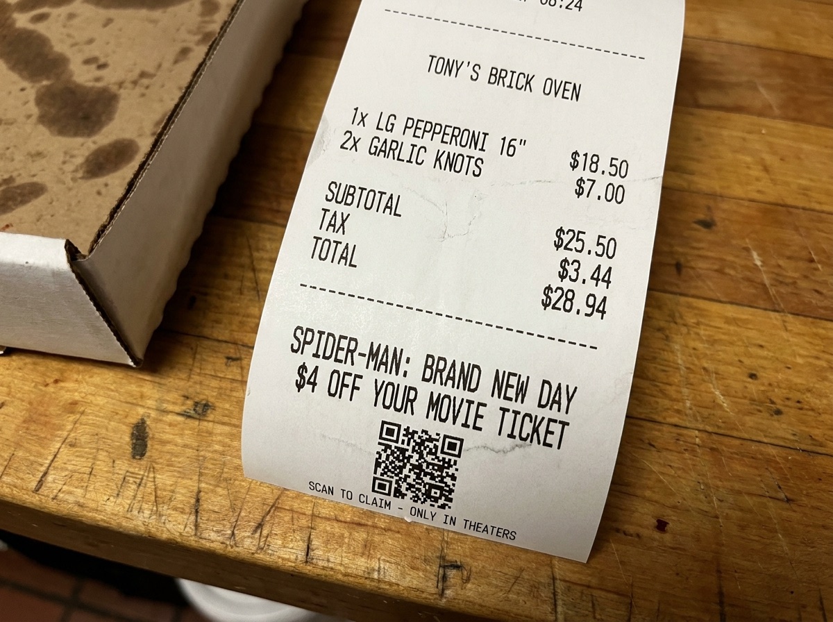 Receipt tape printed with a movie-ticket ad and QR code